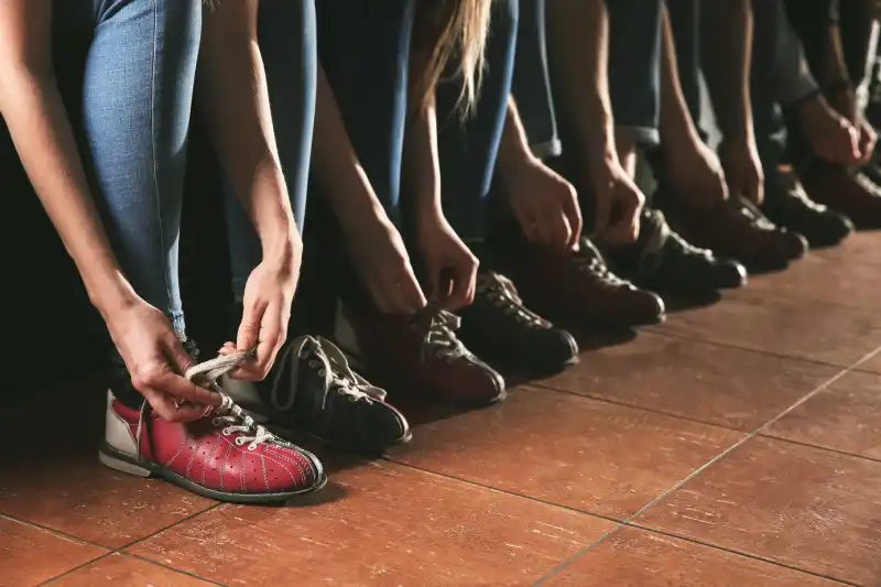PUTTING THE “FUN” IN FUNDRAISING Friends changing shoes before playing bowling in club